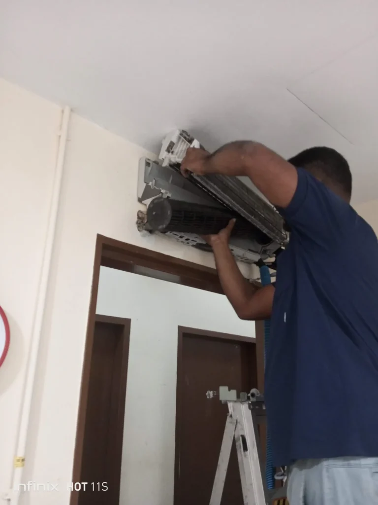 Professional technician servicing and repairing an indoor wall-mounted split system air conditioner unit.