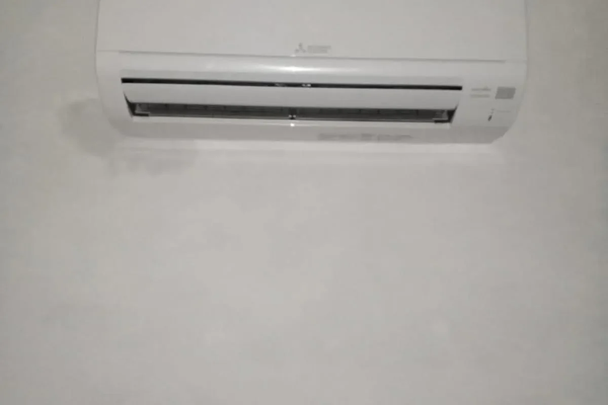 White wall-mounted Mitsubishi Electric air conditioner unit installed on a freshly painted white wall.
