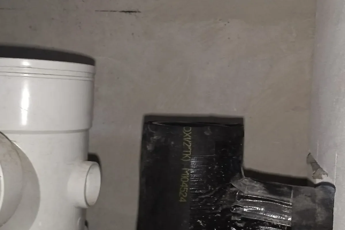 PVC and insulated drainage pipes installed inside a ceiling cavity for air conditioner plumbing.