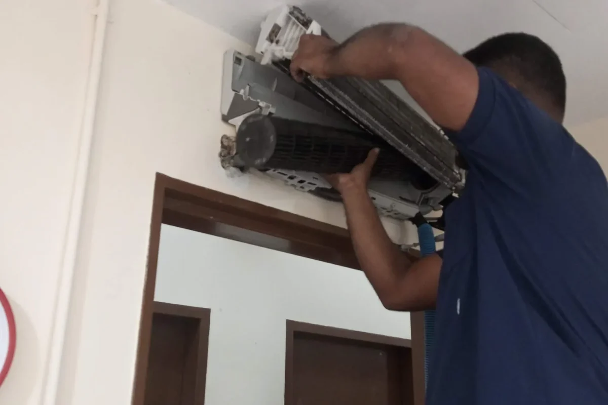 Professional technician servicing and repairing an indoor wall-mounted split system air conditioner unit.